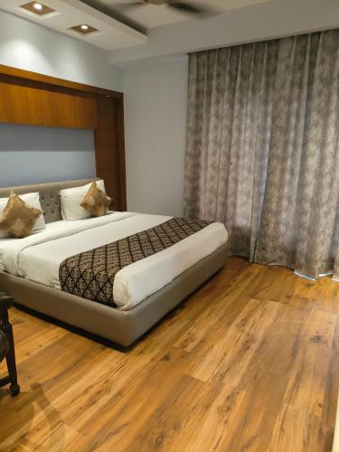 a bedroom with a large bed with a wooden floor at Hotel The Pearl, City Center - Traveler's Choice Award Winner for 2025 in New Delhi