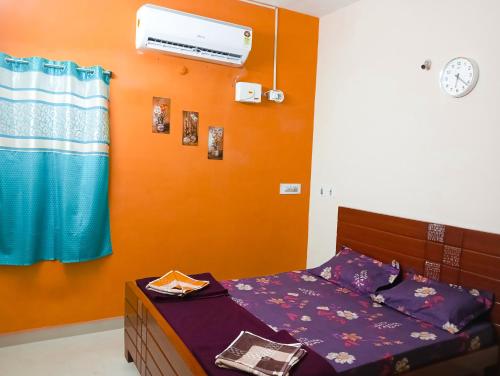 a bedroom with a bed and an orange wall at Jas Homestay Madurai in Tirupparangunram