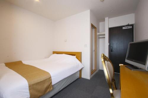 a bedroom with a bed and a flat screen tv at ビジネスホテル 山手INN in Iidamachi