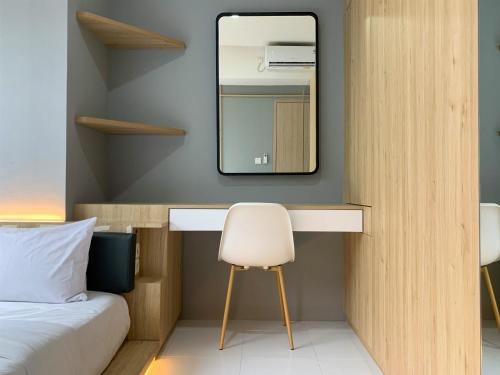 a bedroom with a desk with a mirror and a chair at Comfortable and Spacious 1BR Tokyo Riverside PIK 2 Apartment By Travelio in Rawalembang