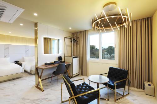 a hotel room with a bed and a table and chairs at Hotel The One in Gangneung