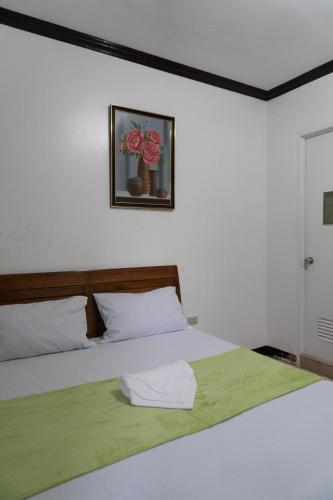a white bedroom with a bed with a green blanket at Shelves Siargao in General Luna