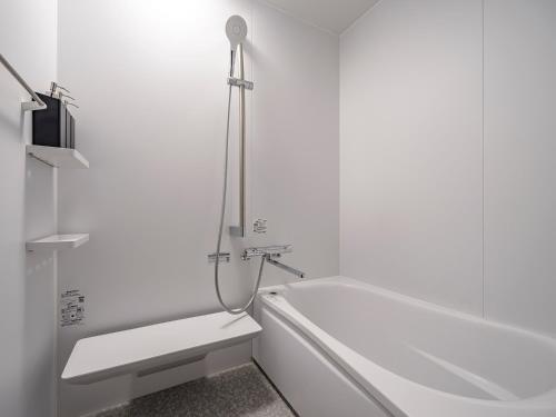 a white bathroom with a tub and a toilet at Arcade Hotel in Fuji