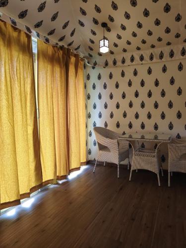 a room with yellow curtains and a table and chairs at The Purple County - Homestay in Lonavala