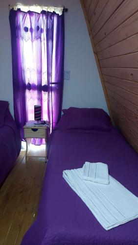 a bedroom with a purple bed with a window at Cabaña la turka in Perito Moreno