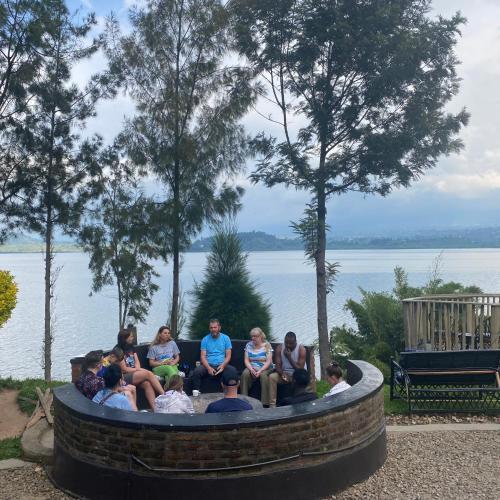 a group of people sitting in a circular circle with the water at Ruhondo Beach Resort in Ruhengeri