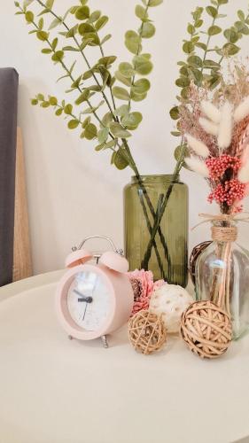 a table with a clock and a vase with flowers at Apartments nahe der Südsteirischen Weinstraße in Straß in Steiermark