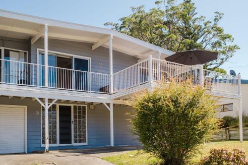 a house with a balcony and an umbrella at Our Molly in Mollymook
