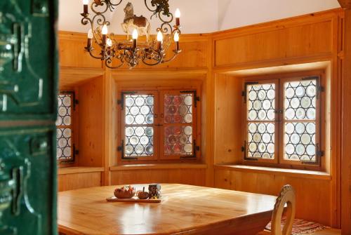 a dining room with a wooden table and windows at Ferienunterkünfe Beim Posthalter in Oberammergau