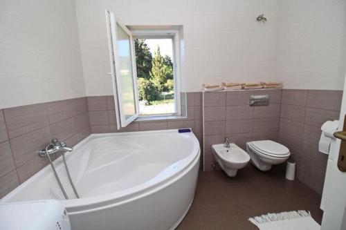 a bathroom with a large tub and a toilet at Apartment with terrace and garden in Vela Luka