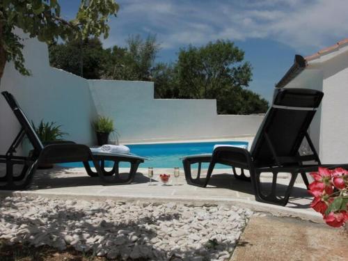 two chairs and a table next to a pool at Holiday House Pine Tree - Three Bedroom Holiday Home with Pool in Nerežišća