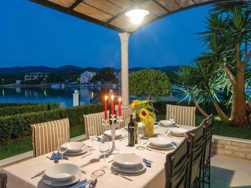 a table with candles and plates and chairs on a patio at Holiday Home Lovi te-Three Bedroom Holiday Home with Pool and Sea View in Lovište