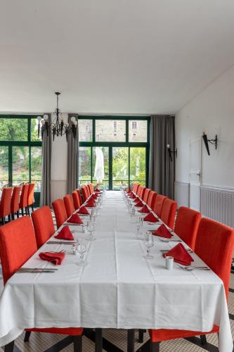 a long table with red chairs in a room at Hôtel Restaurant Du Château in Josselin