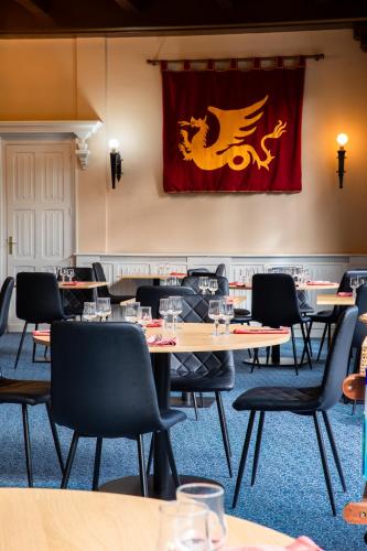 a dining room with tables and chairs with a dragon flag at Hôtel Restaurant Du Château in Josselin