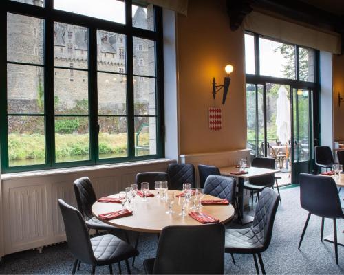 a dining room with tables and chairs and windows at Hôtel Restaurant Du Château in Josselin
