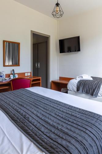 a hotel room with a bed and a tv at Hôtel Restaurant Du Château in Josselin