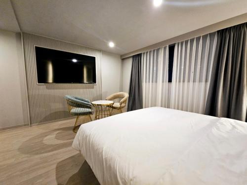 a hotel room with a bed and a table and chairs at Daeyeon Grandis Hotel in Busan