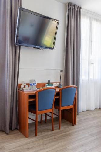 a desk with two chairs and a television on a wall at Hôtel Restaurant Du Château in Josselin