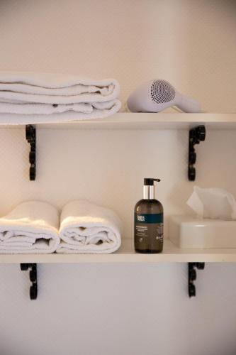 a bathroom shelf with towels and a bottle of soap at Hôtel Restaurant Du Château in Josselin