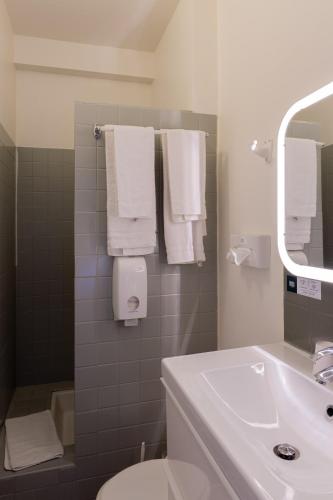 a bathroom with a sink and a toilet and towels at Hôtel Restaurant Du Château in Josselin