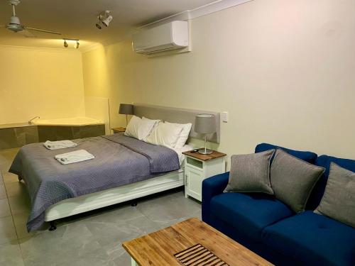 a bedroom with a bed and a blue couch at Villa 25 Coral Cove Resort in Bargara