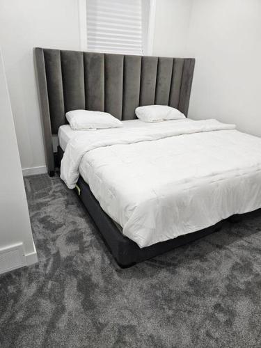 a large bed with a large headboard in a bedroom at Comfort Guest Suite NE Calgary - Near Airport in Calgary