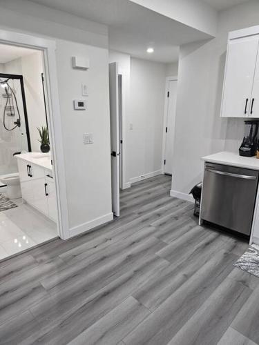 a kitchen with white walls and a wooden floor at Comfort Guest Suite NE Calgary - Near Airport in Calgary