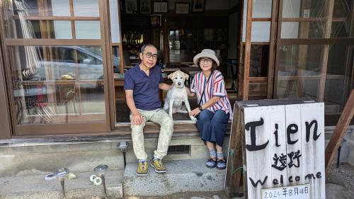 a man and a woman sitting in a doorway with a dog at Lien Tono in Tōno