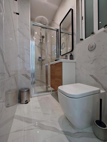 a white bathroom with a toilet and a shower at Seascape 19 in Mellieħa
