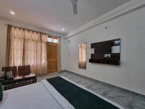 a bedroom with a bed and a television on the wall at Baikunth Homes in Dalhousie