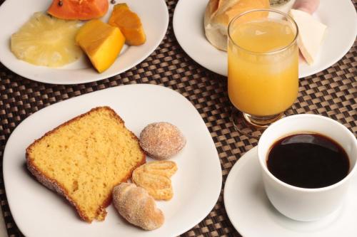 a table with plates of food and a glass of orange juice at Sul América Palace Hotel in Belo Horizonte