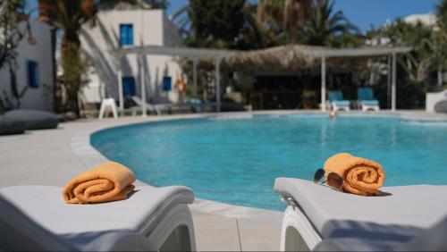 a swimming pool with a pair of towels on the backs of chairs at Lakki Village in Aegiali