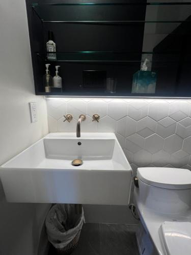 a white bathroom with a sink and a toilet at Charming 2BR Cottage with Bay and City Views-Gated Luxury Private Place in San Francisco