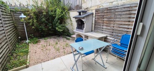 a patio with a table and chairs and a fireplace at T3 spacieux lumineux jardin et proche du tram in Pont-de-la-Maye