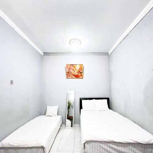 two beds in a room with white walls at Q-Five Guest House YIA Kulon Progo Mitra RedDoorz in Temon