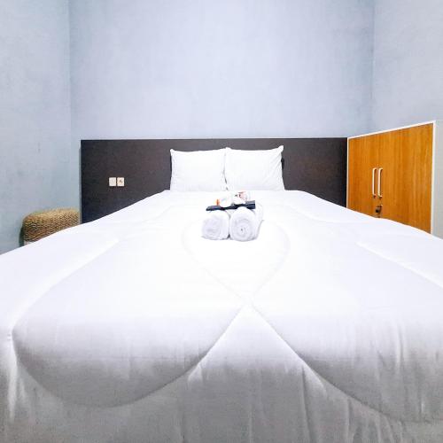 a white bed with two rolls of towels on it at Q-Five Guest House YIA Kulon Progo Mitra RedDoorz in Temon