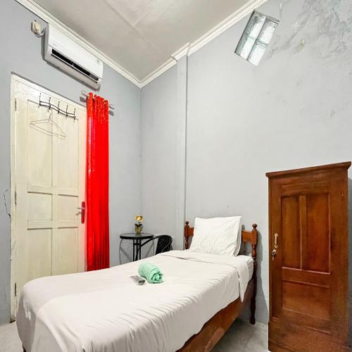 a bedroom with a bed and a red curtain at Q-Five Guest House YIA Kulon Progo Mitra RedDoorz in Temon