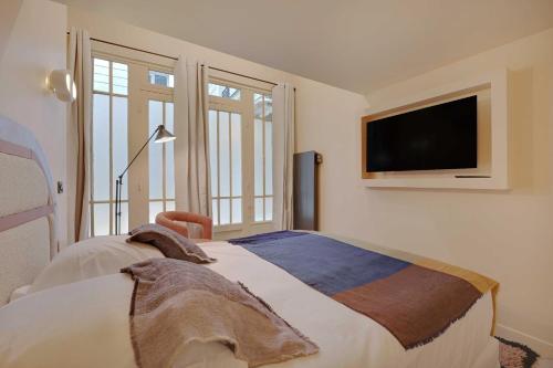 - une chambre avec un lit et une télévision murale dans l'établissement Exceptional apartment - 4BR-8P- Le Marais, à Paris