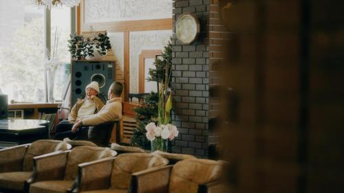 two people sitting in a room with a clock at Hotel Japan Shiga in Yamanouchi