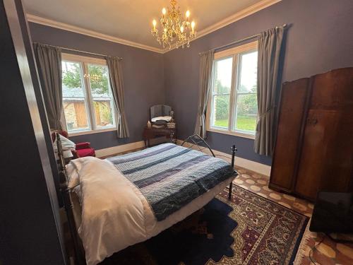 1 dormitorio con cama, ventanas y lámpara de araña en Cockayne Hatley Hall, en Cockayne Hatley