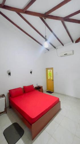 a bedroom with a red bed in a white room at White Eagle Hotel in Sigiriya