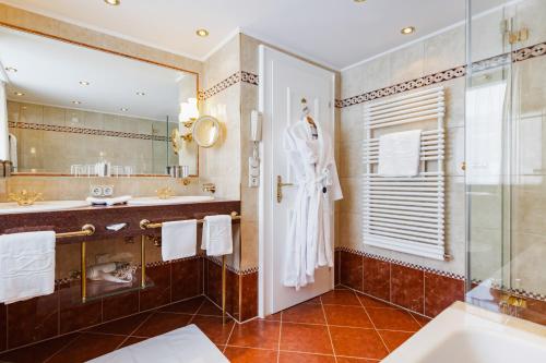 a bathroom with a sink and a robe on a door at Hotel Zürserhof in Zürs am Arlberg