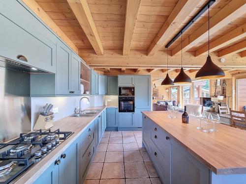 Il comprend une grande cuisine avec des placards bleus et des plafonds en bois. dans l'établissement Chalet 4 Saisons - 10pers - proche piste, aux Gets