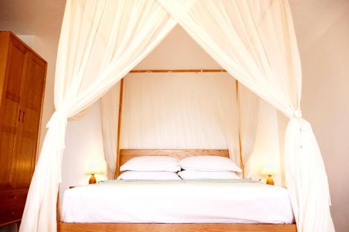 a bedroom with a canopy bed with white curtains at Blue Whale Villa - Deluxe in Calibishie