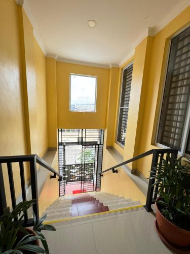 a staircase in a building with yellow walls and windows at Urbanview Botania Meeting Point Batam by RedDoorz in Nongsa