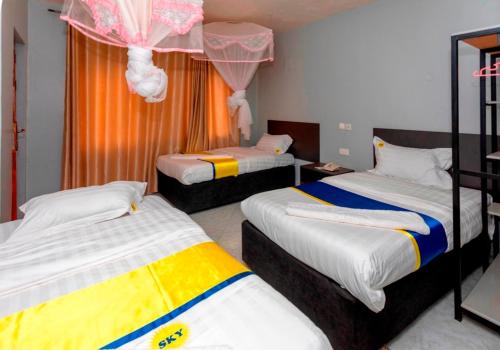 a room with three beds in a room at Sky Beach Hotel in Wakiso
