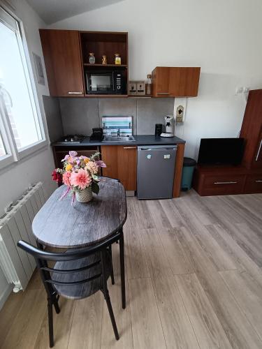 eine Küche mit einem Tisch mit einer Vase mit Blumen darauf in der Unterkunft Logement pour 2 personnes proche Bordeaux in Le Haillan