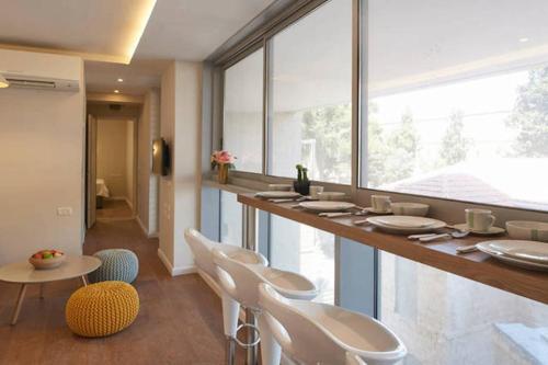 a room with a bar with white chairs and windows at Chic & Quiet Apartments in City Center by FeelHome in Jerusalem