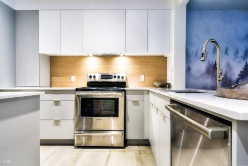 a kitchen with white cabinets and a stainless steel oven at Chic Mt-Tremblant Condo with View on the Lake by Denstays in Mont-Tremblant