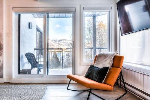 an orange chair sitting in front of a window at Chic Mt-Tremblant Condo with View on the Lake by Denstays in Mont-Tremblant